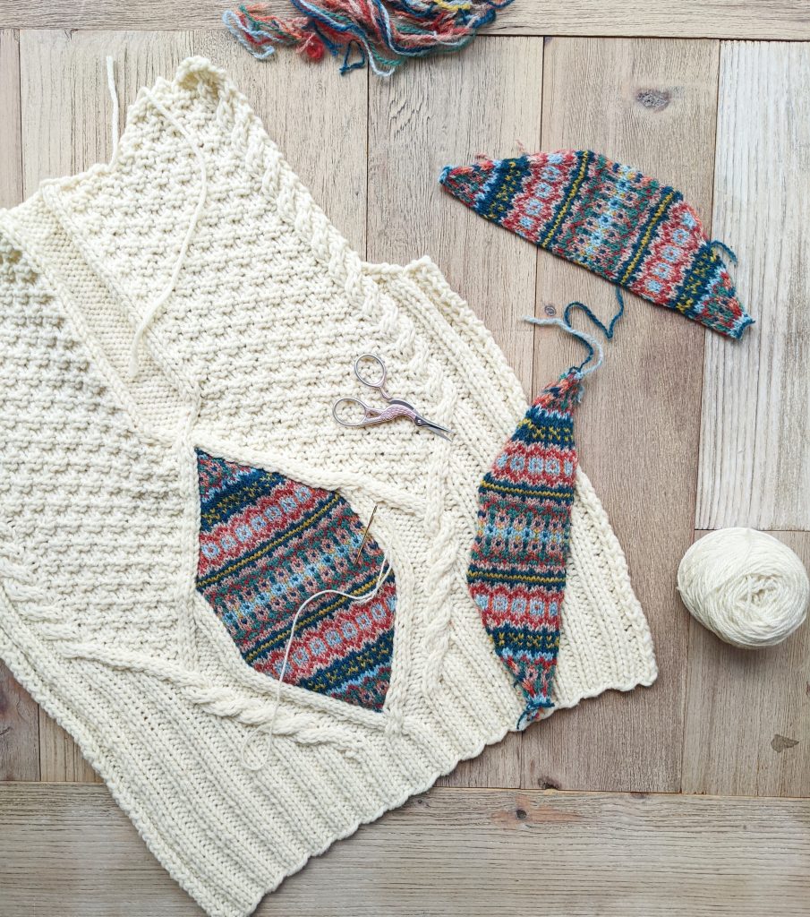 work in progress Aurora Cardigan with the colourwork swatches laid beside the base layer of the cardigan